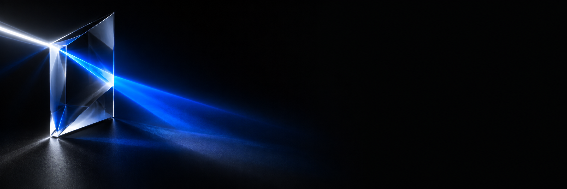 A clear glass prism on black with a beam of light entering it and refracting into blue